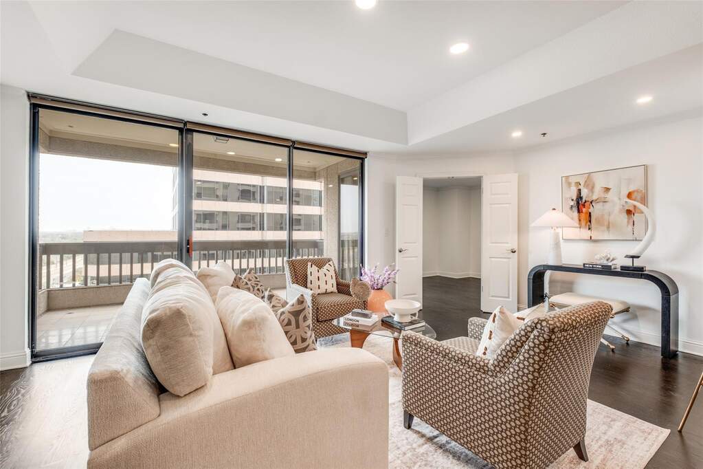 Relax in a living room bathed in natural light. The oversized glass sliders offer an incredible urban view, while the layout provides ample space for a full seating arrangement-ideal for both