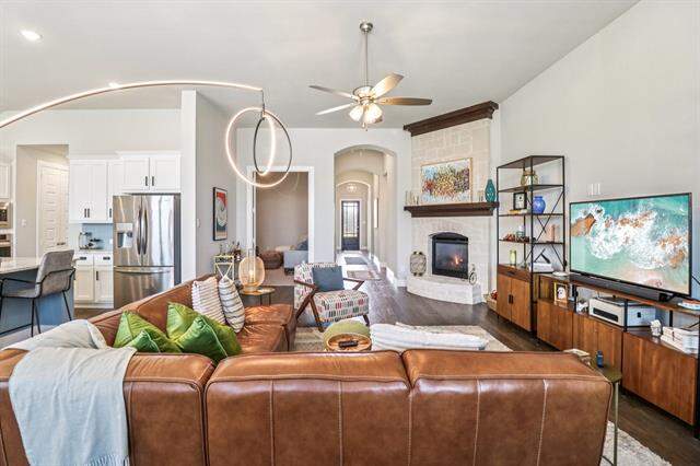 Living area with ceiling fan, dark wood finished floors, a fireplace, and arched walkways