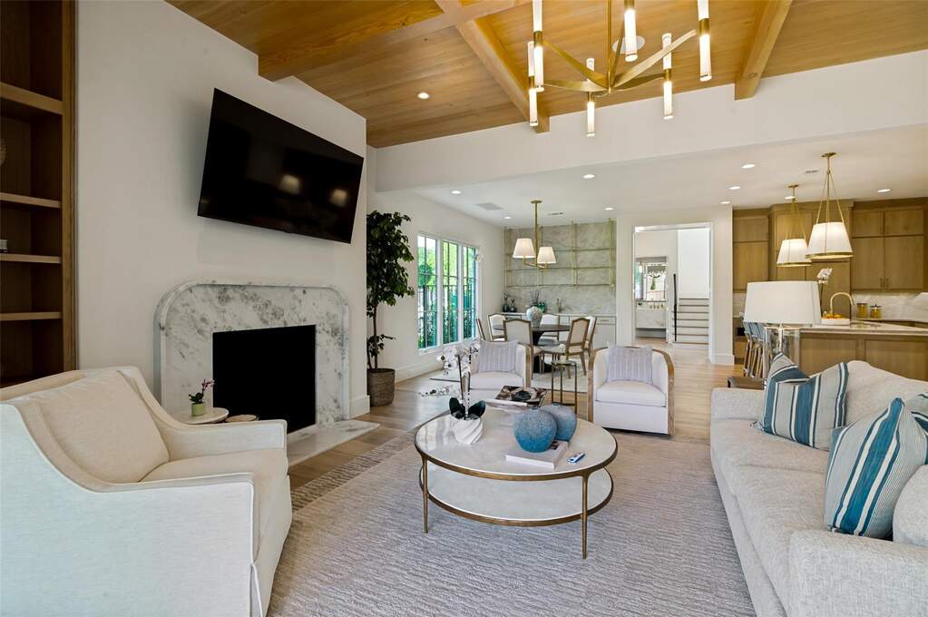 Living area featuring a marble-surround fireplace, wood-finish flooring, and a vaulted wood-paneled ceiling with an angular brass chandelier