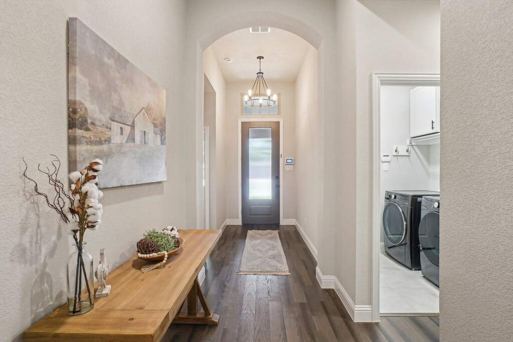 Foyer entrance with a chandelier, dark wood finished floors, arched walkways, washer and dryer, and a textured wall