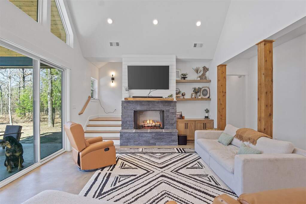Living area with recessed lighting, lofted ceiling, and a stone fireplace