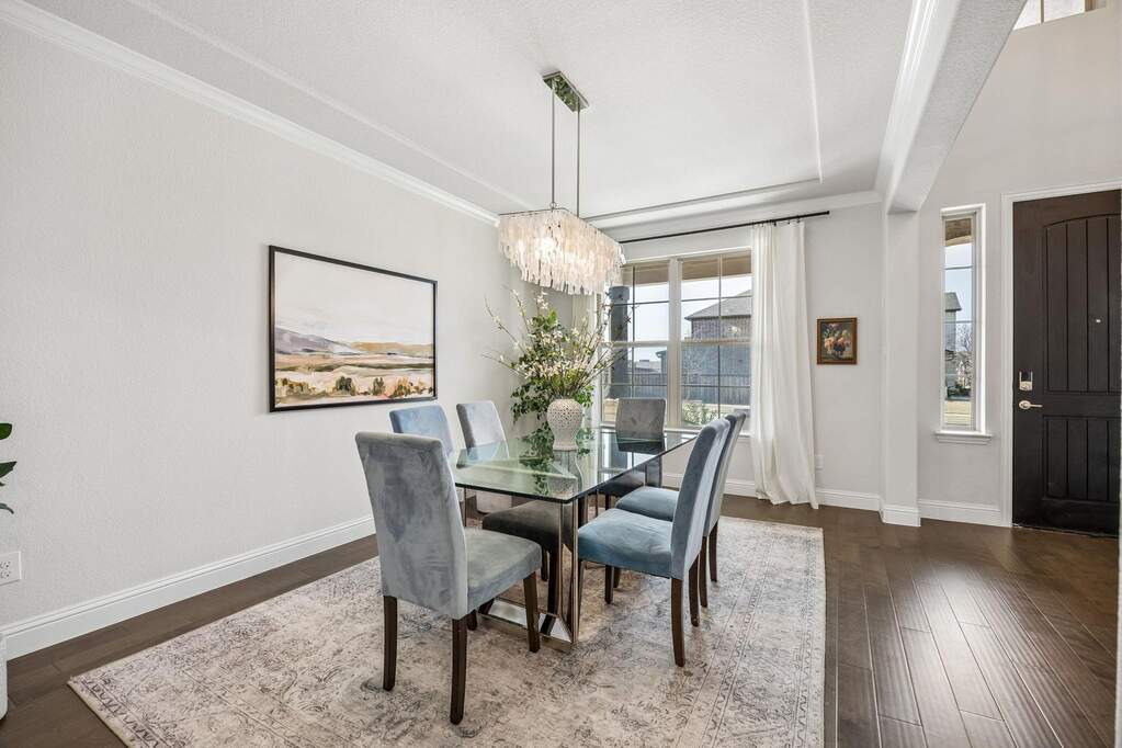 Dining space with suspended lighting, ornamental molding, and dark wood-style floors