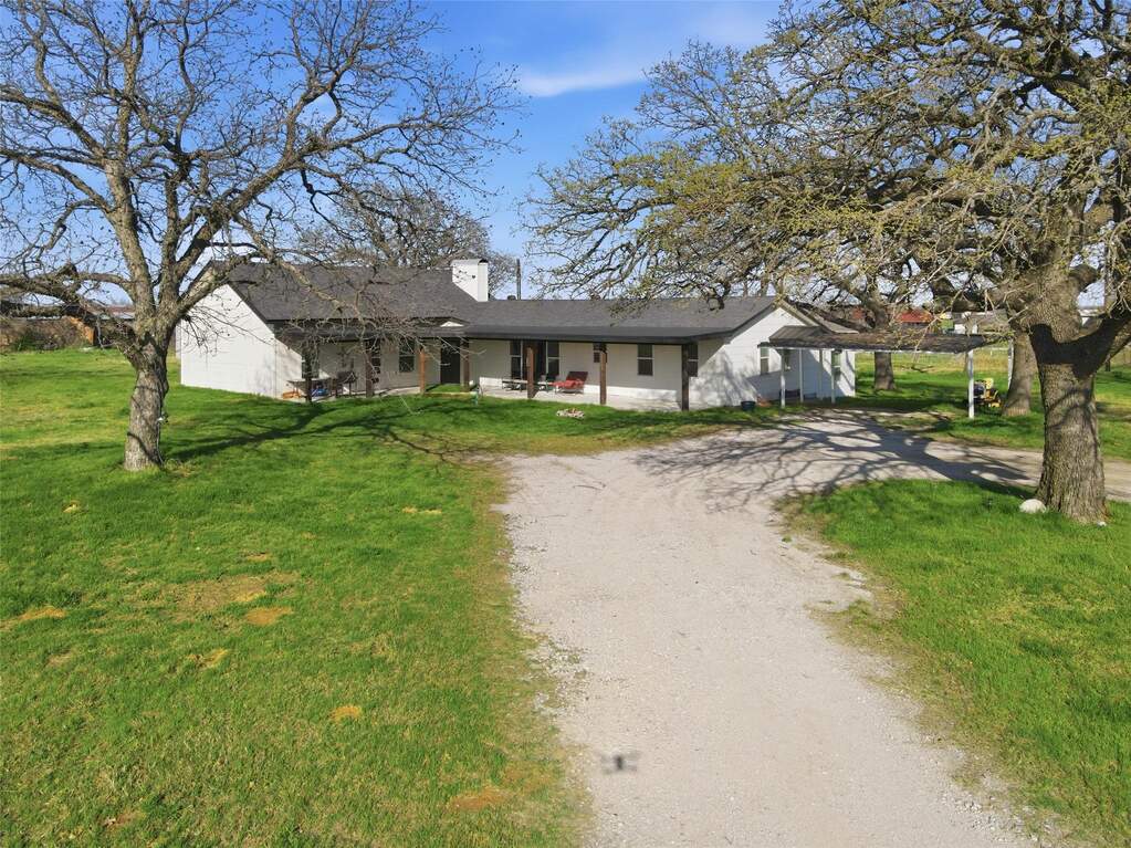 Ranch-style home featuring dirt driveway, a front lawn, and a chimney