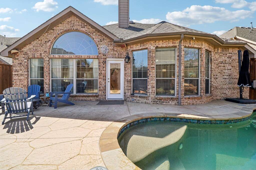 Rear view of property featuring an outdoor pool, a patio area, and brick siding