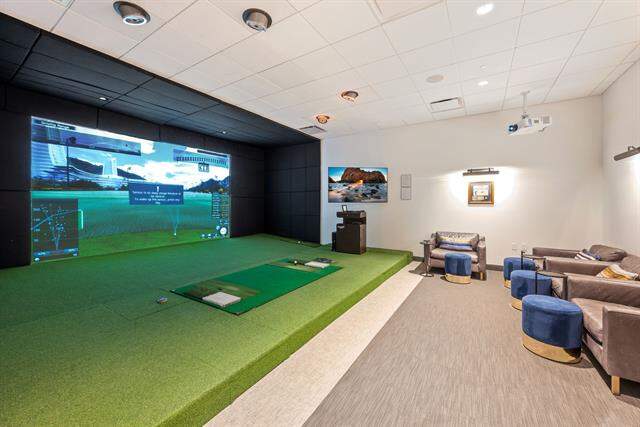 Recreation room in the common area with golf simulator, carpet flooring, and a paneled ceiling