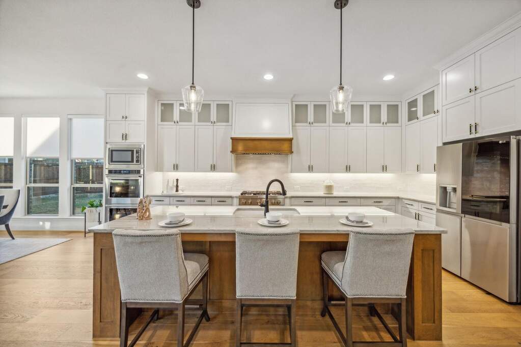 Kitchen with pendant lighting, a kitchen island with sink, and appliances with stainless steel finishes