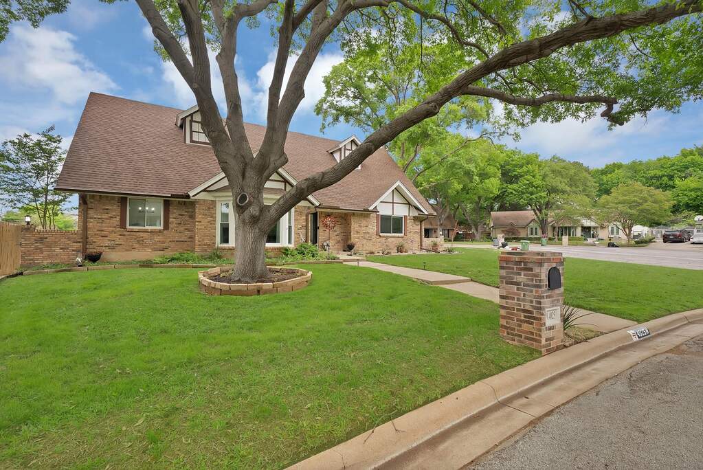 View of front facade featuring a front yard, brick siding, and roof with shingles