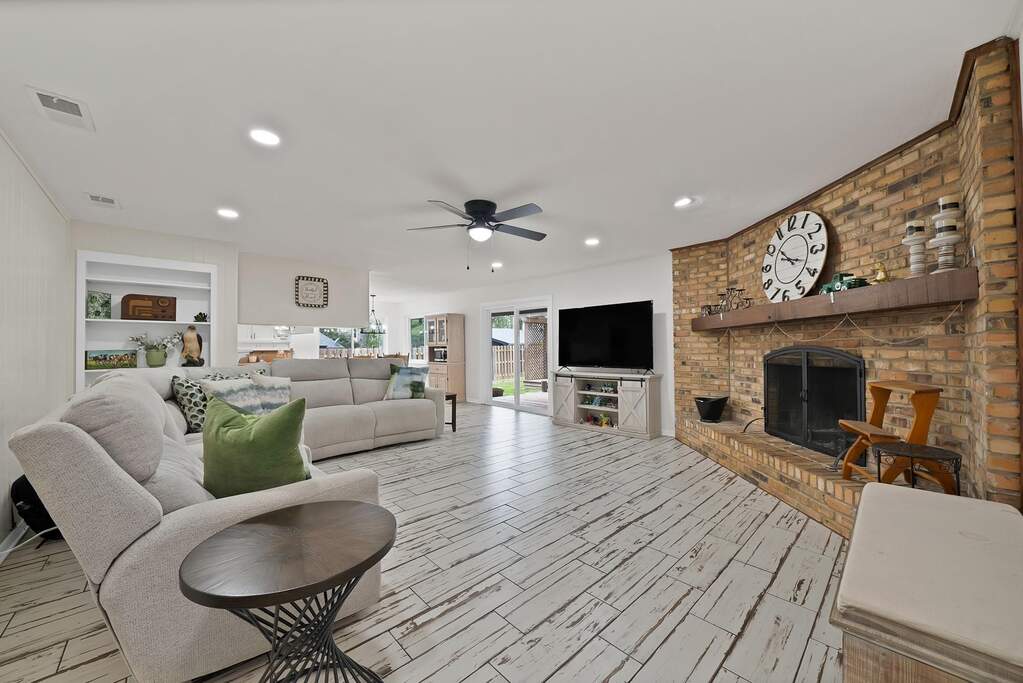 Living room with a fireplace, built in features, ceiling fan, wood finish floors, and recessed lighting