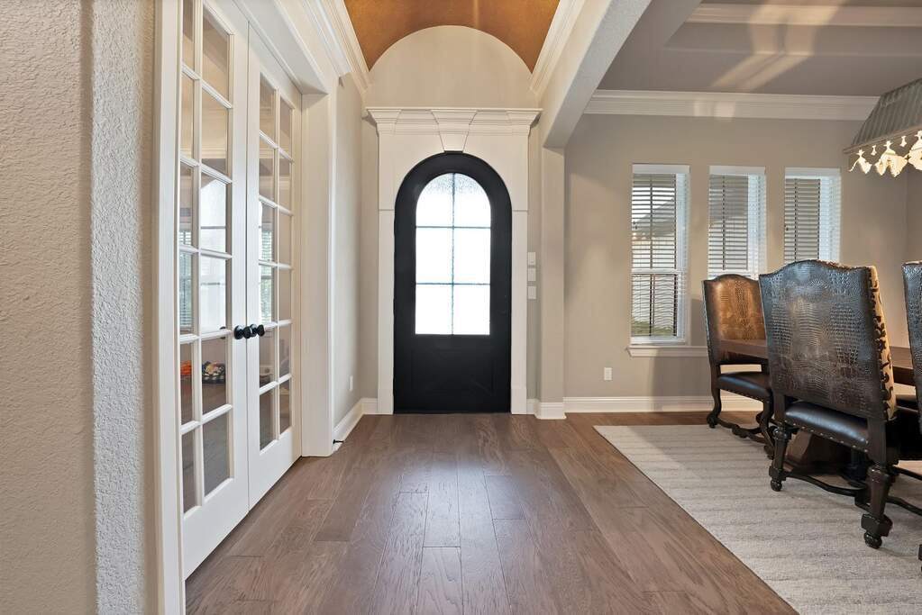 Foyer featuring ornamental molding, lofted ceiling, a chandelier, and wood-type flooring