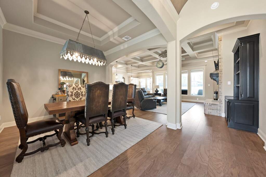 Dining room featuring crown molding, hardwood / wood-style flooring, coffered ceiling, and a raised ceiling