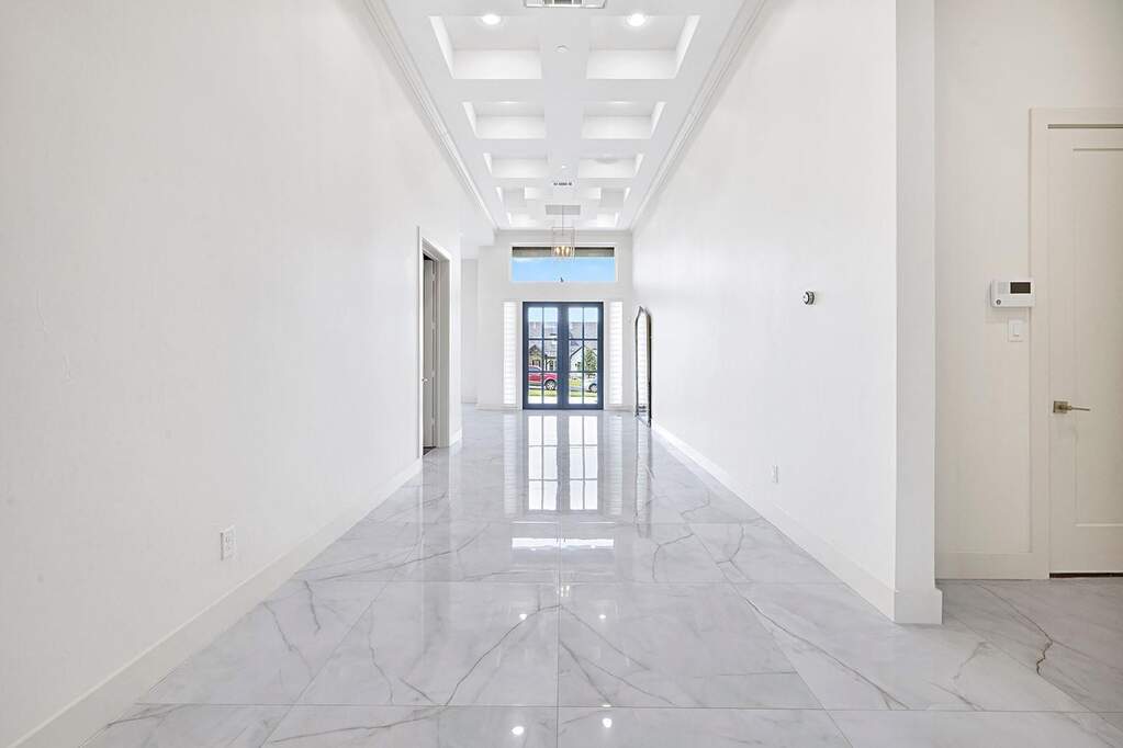 Long hallway with high ceilings featuring a coffered design and recessed lighting