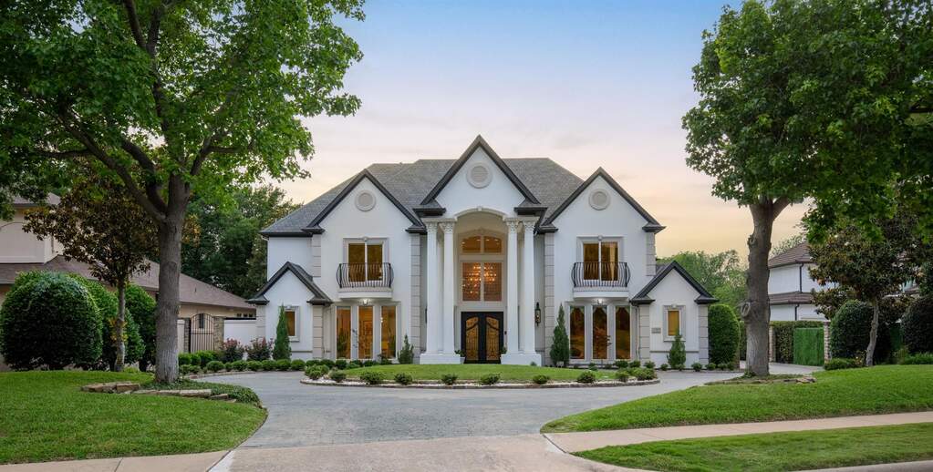 Stately residence featuring a circular driveway, prominent classical columns, and a grand double-door entry