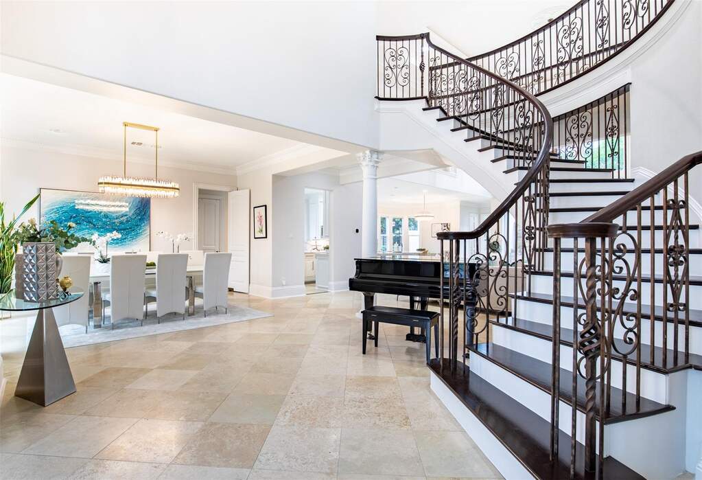Grand foyer featuring an ornate curved staircase with wrought iron balusters and dark wood treads
