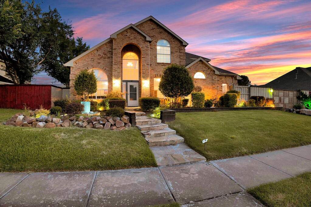 Brick exterior featuring arched windows, a stone pathway, and a landscaped front yard with a rock border