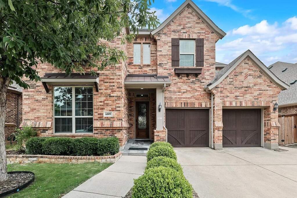 Classic brick exterior with gabled rooflines, a two-car garage with carriage-style doors, and a covered entry