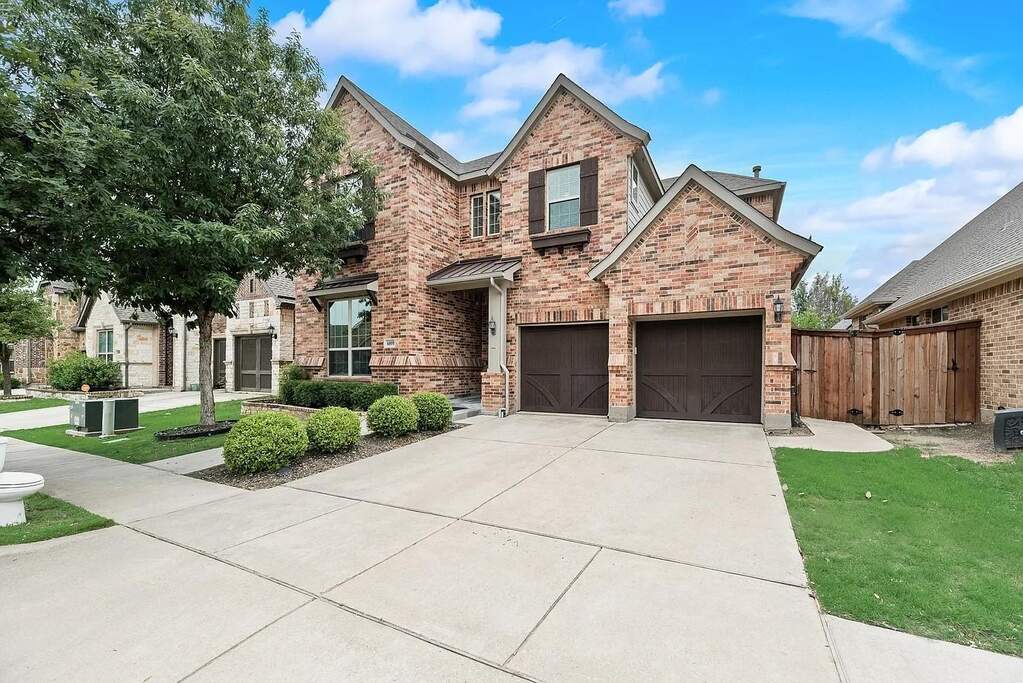 Brick exterior featuring a gabled roofline and a two-car garage with carriage-style doors