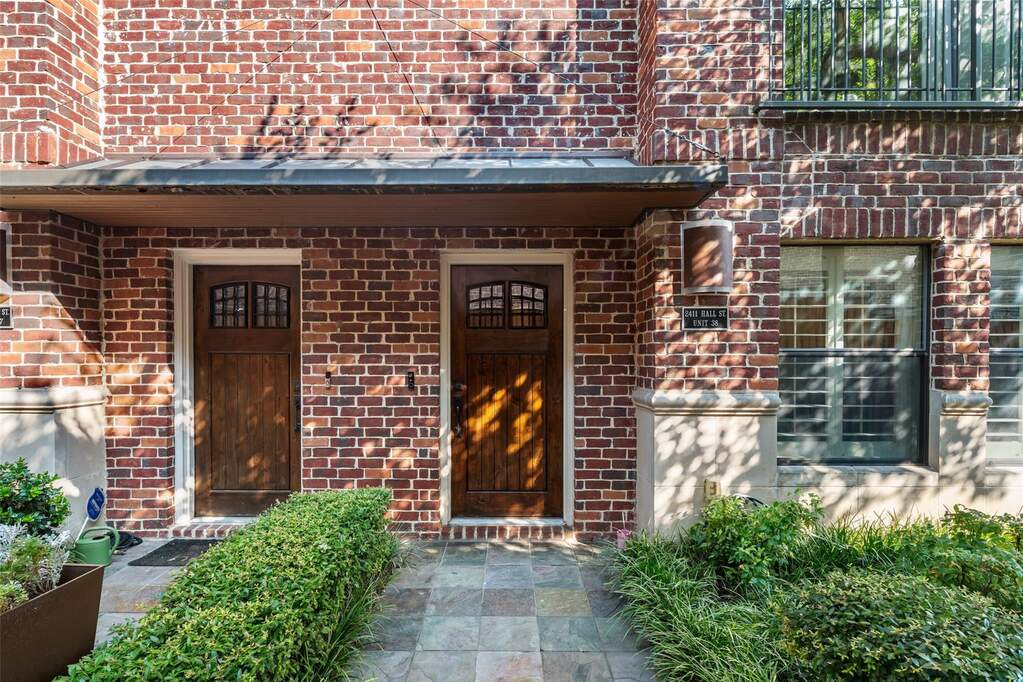 Brick facade entry featuring two wood-panel doors with transom windows