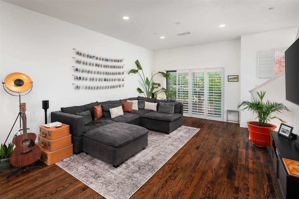 Living area featuring rich wood-finish flooring, white walls, and recessed lighting