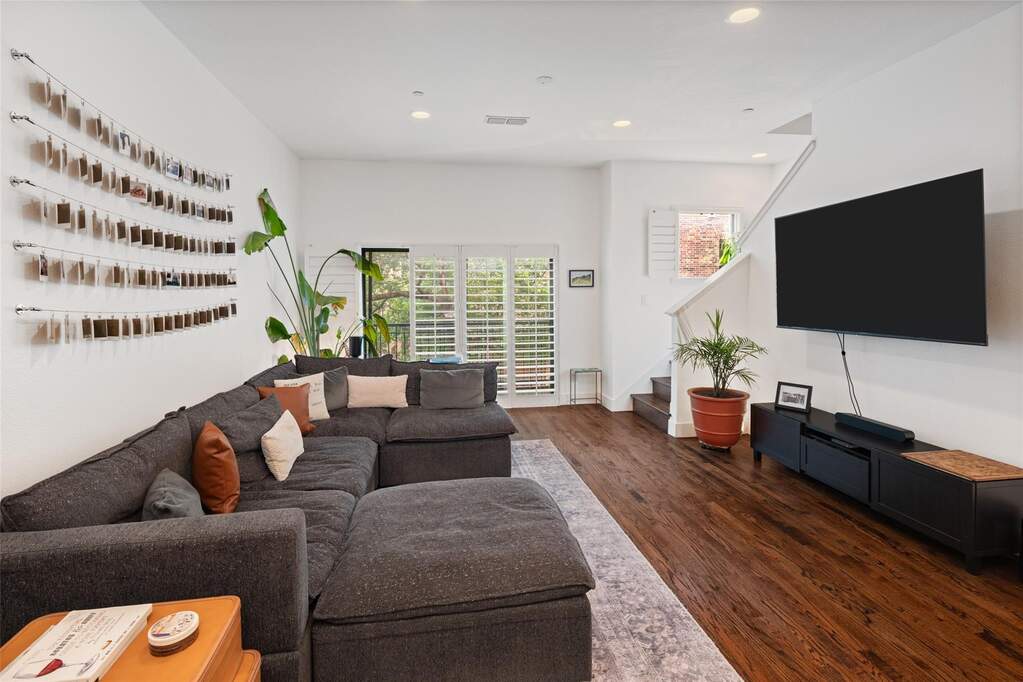 Living area featuring rich wood-finish flooring, recessed lighting, white walls, and a staircase with white risers and dark wood treads