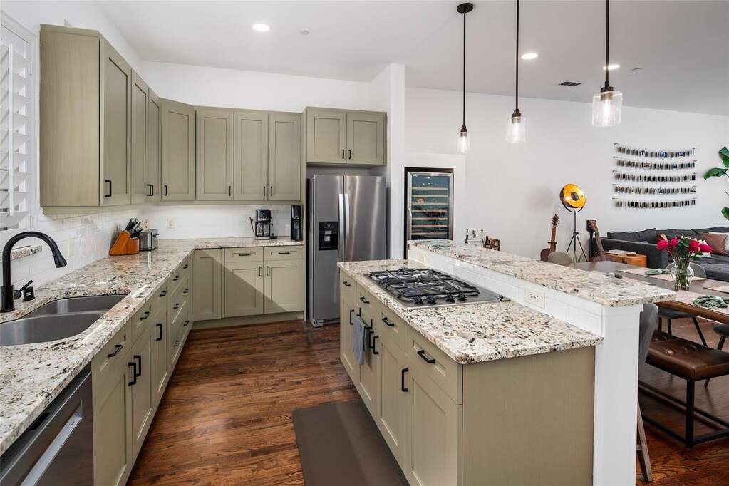 Kitchen featuring light-toned cabinetry, granite countertops, stainless steel appliances, and wood-finish flooring