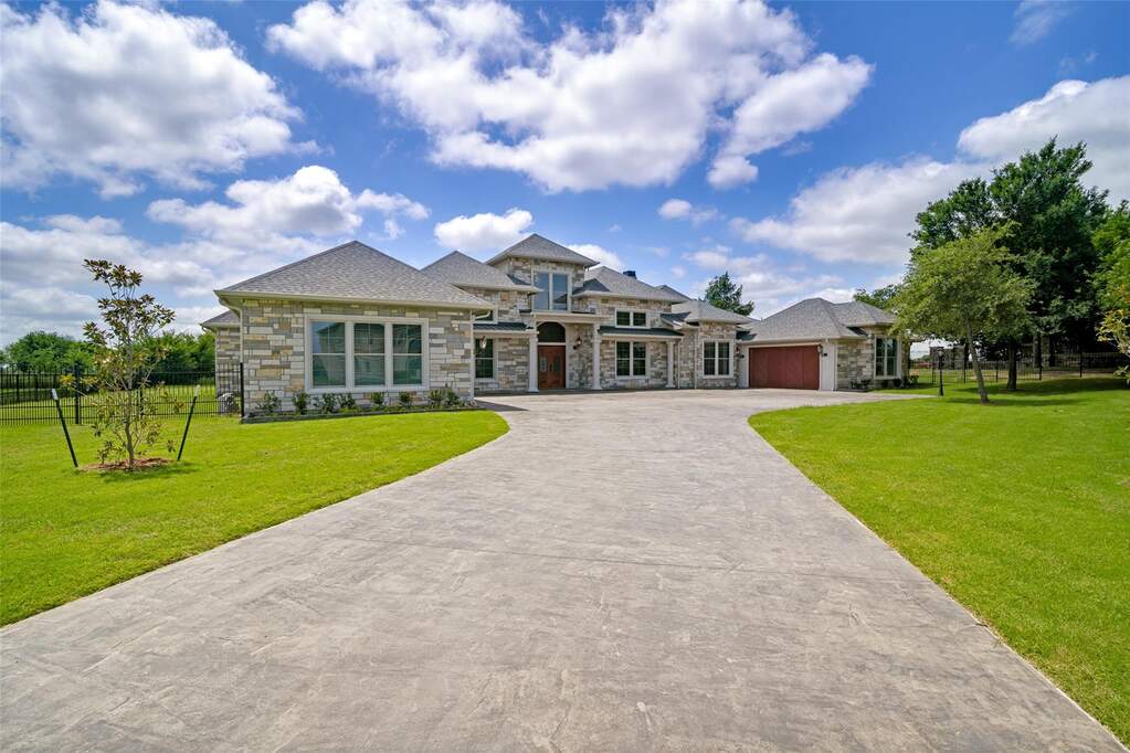 Stone facade residence featuring a multi-gabled roofline and an expansive stamped concrete driveway