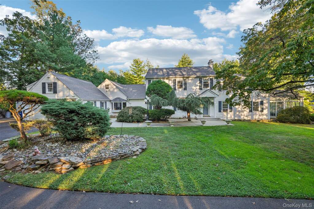 Colonial house featuring a chimney, a front lawn, and a patio area