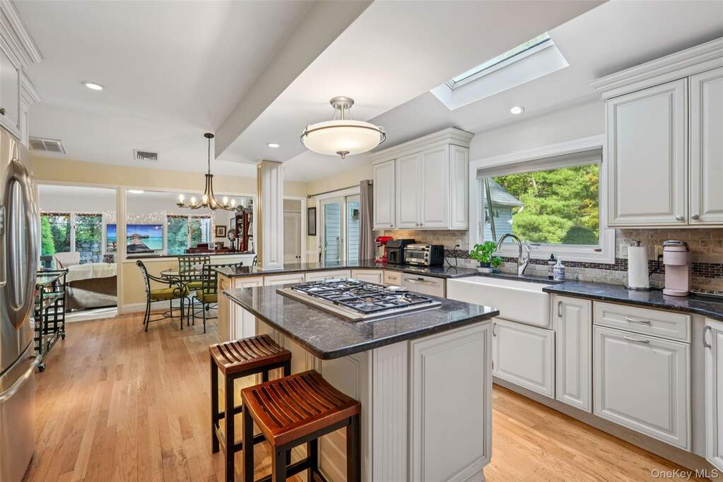 Kitchen featuring tasteful backsplash, dark stone counters, pendant lighting, a kitchen breakfast bar, and recessed lighting
