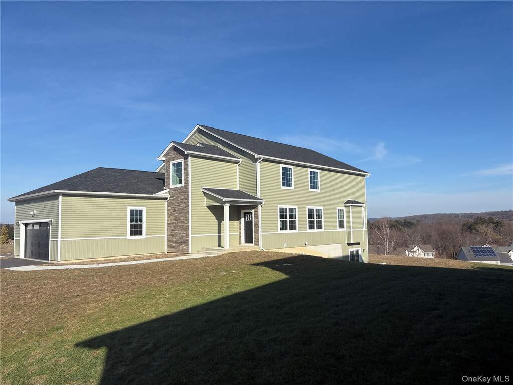 Back of property featuring a lawn, an attached garage, and roof with shingles