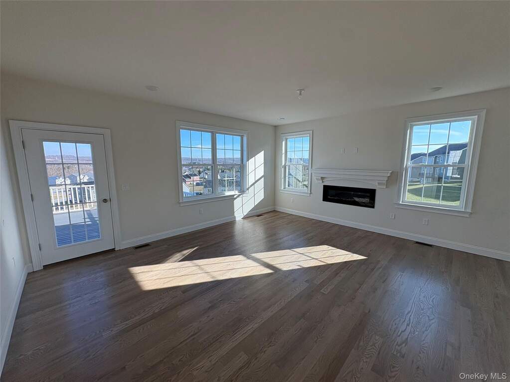 Unfurnished living room with a glass covered fireplace and dark wood-style flooring