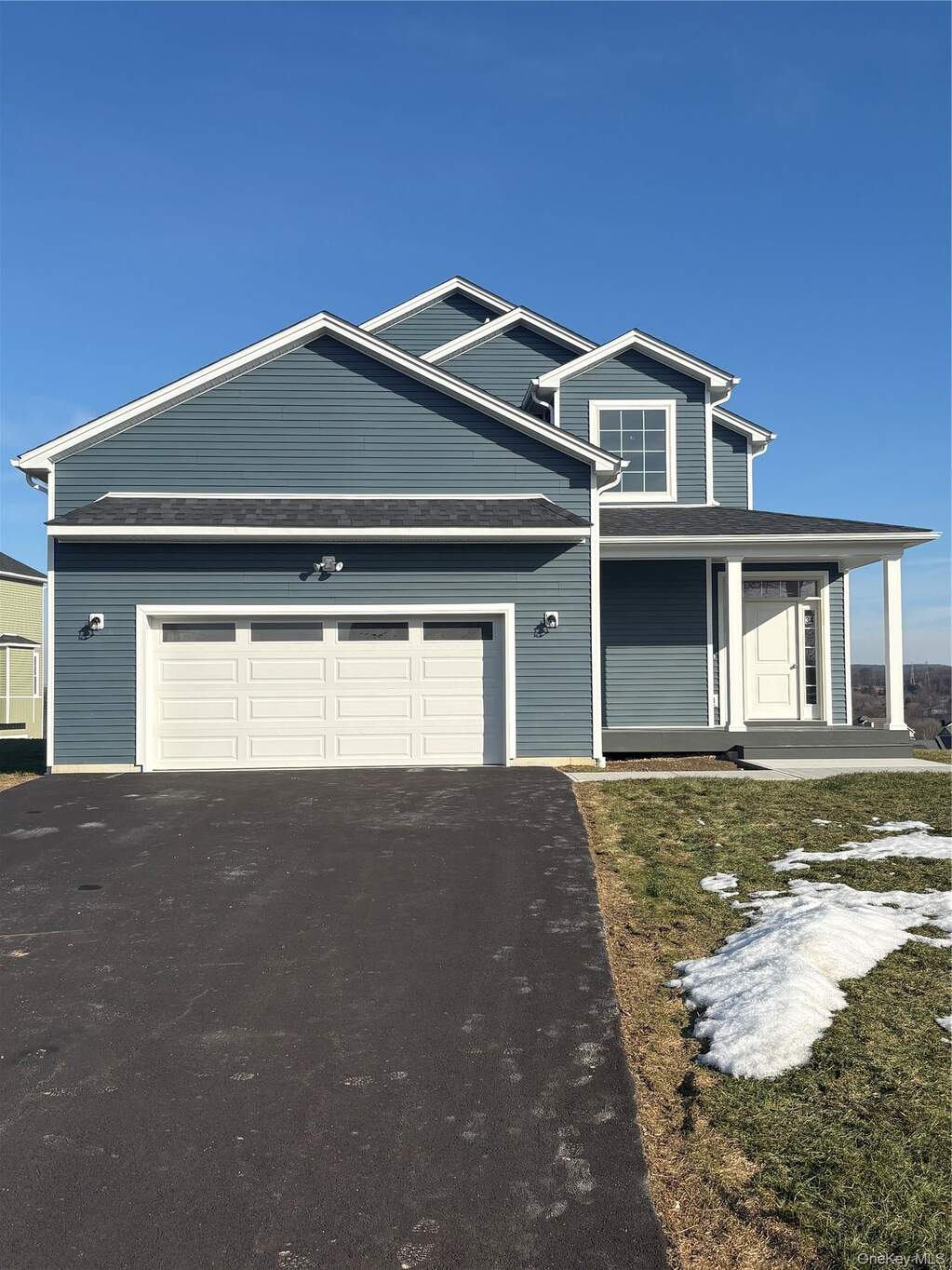 View of front of property featuring driveway, a porch, a garage, and a shingled roof