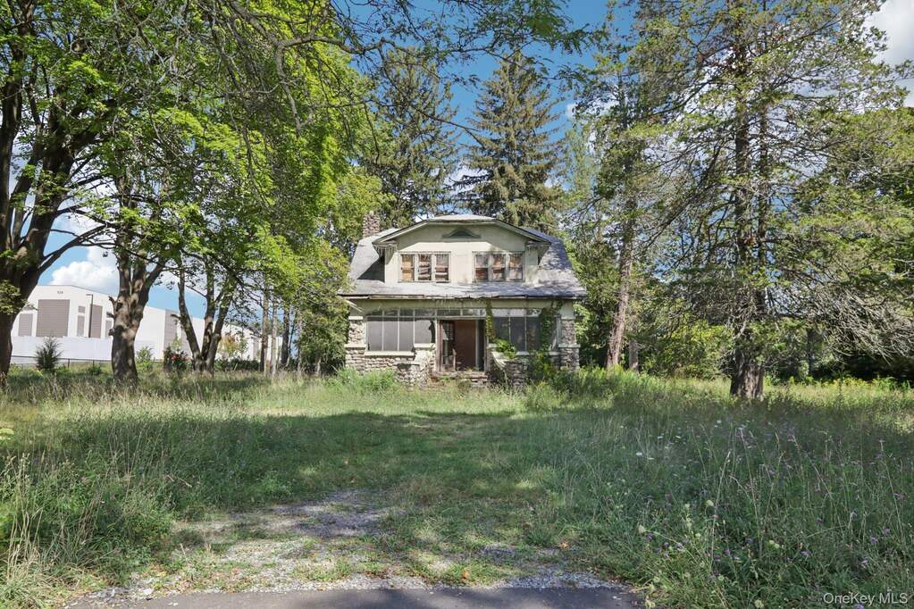 View of front of house featuring stone siding, a chimney, and covered porch