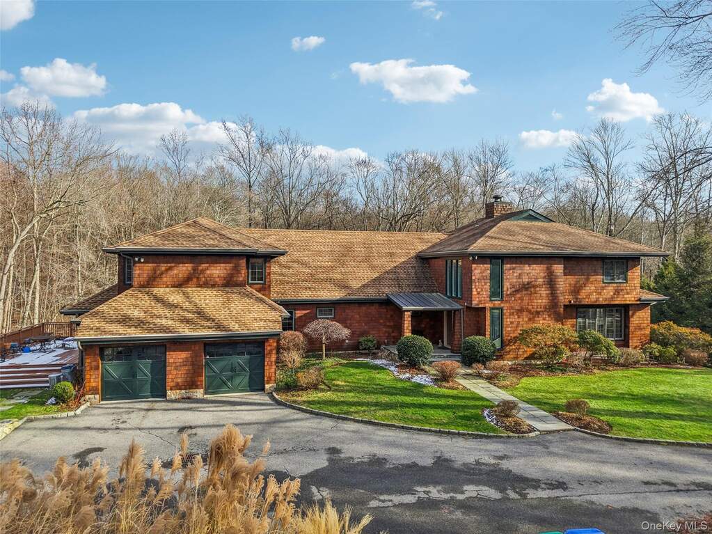 View of front of property with asphalt driveway, a chimney, a front yard, a garage, and a shingled roof