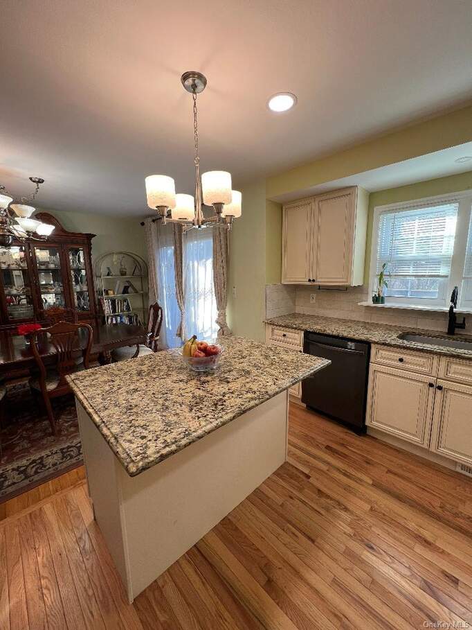 Kitchen with a chandelier, light stone countertops, light wood finished floors, dishwasher, and recessed lighting