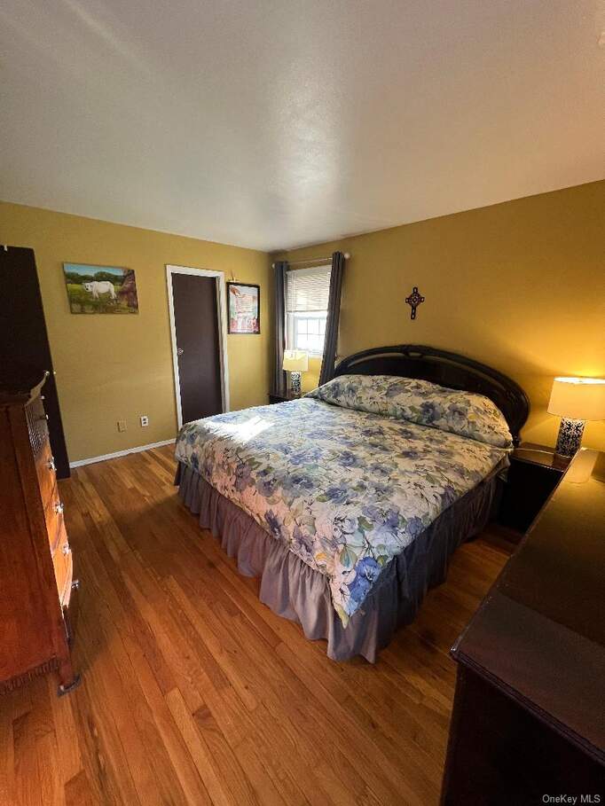 Bedroom with hardwood / wood-style flooring and baseboards