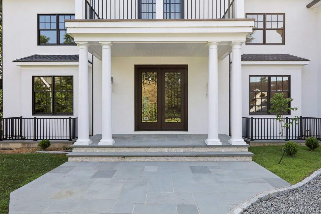 Entrance to property featuring covered porch, a balcony, and stucco siding