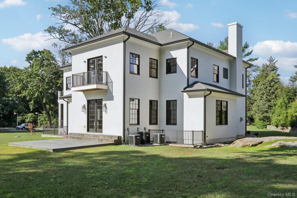 Rear view of property with a balcony, a chimney, stucco siding, a lawn, and a patio area