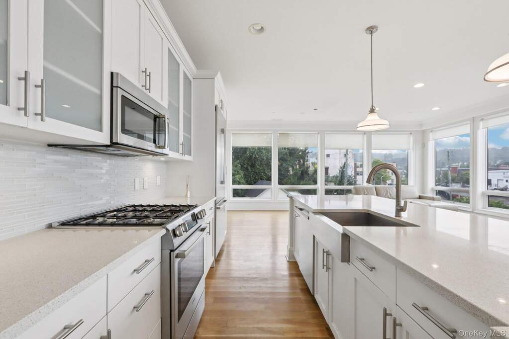 Kitchen featuring appliances with stainless steel finishes, white cabinetry, light stone counters, plenty of natural light, and recessed lighting