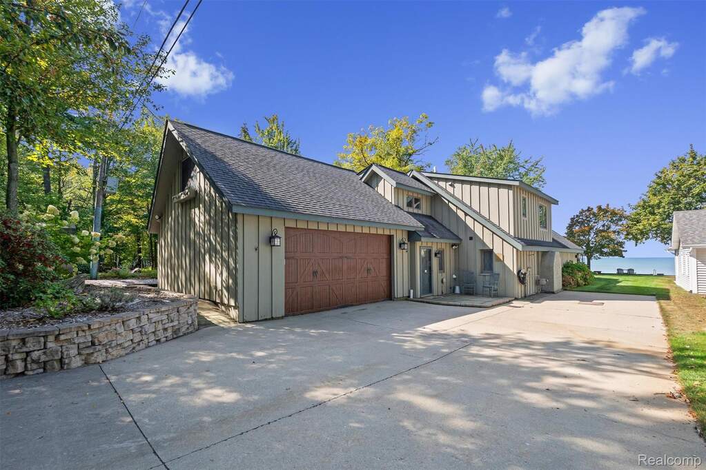 View of front of house with board and batten siding, a shingled roof, concrete driveway, and a garage