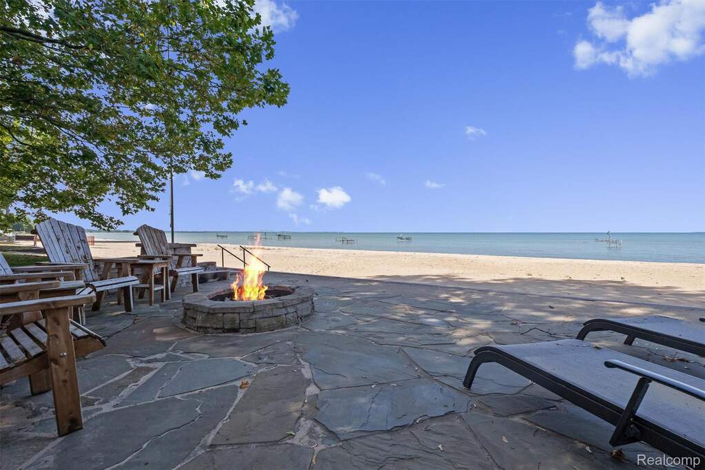 View of patio featuring view of water and beach and an outdoor fire pit