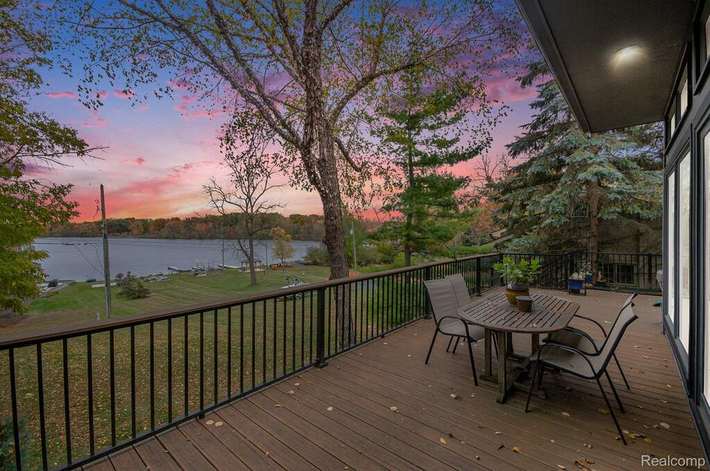Wooden deck featuring outdoor dining area, a water view, and a yard