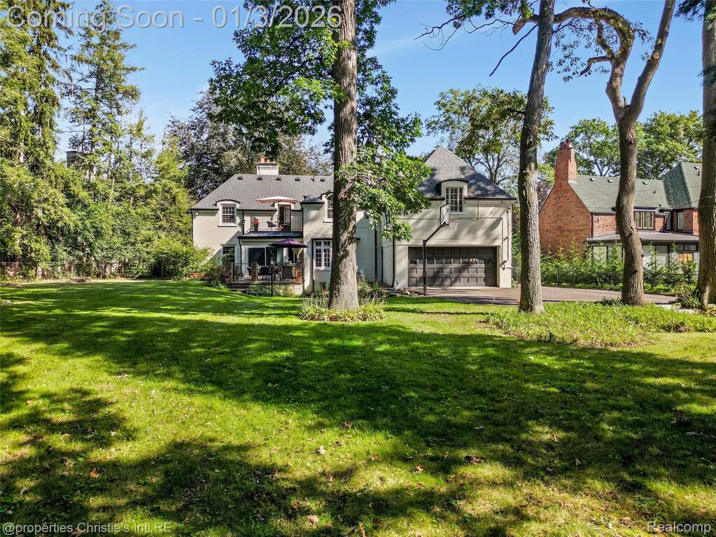 View of green lawn with a garage and concrete driveway