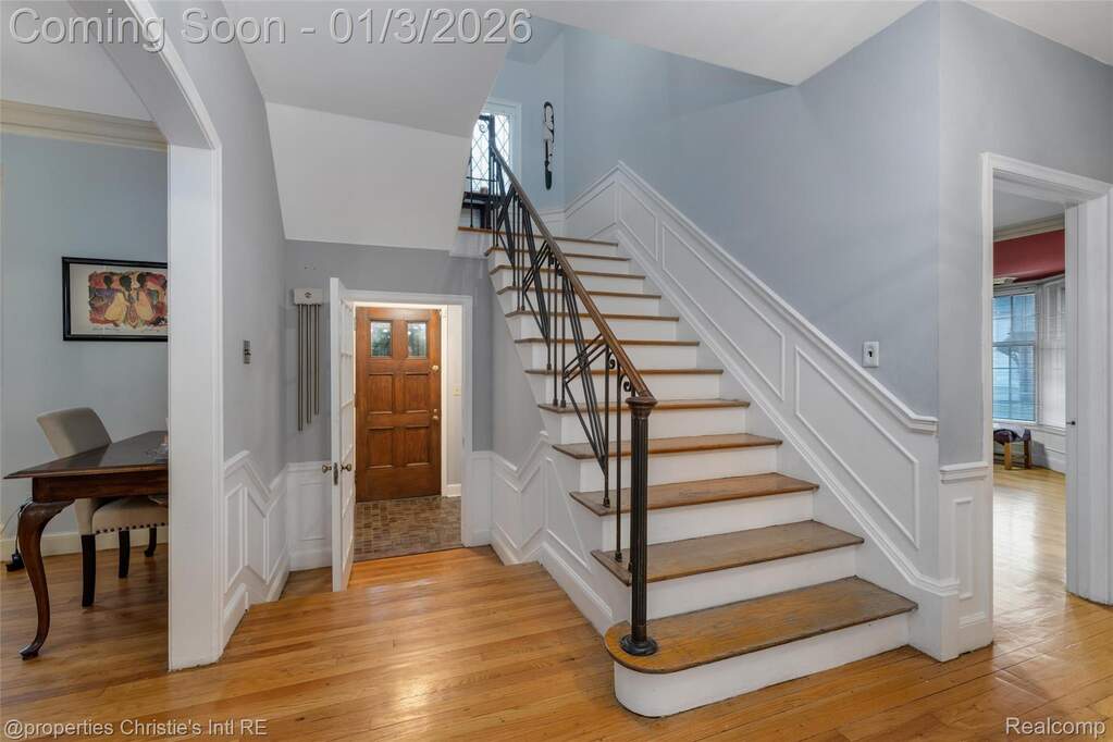 Stairs with hardwood / wood-style flooring, a wainscoted wall, crown molding, and a decorative wall