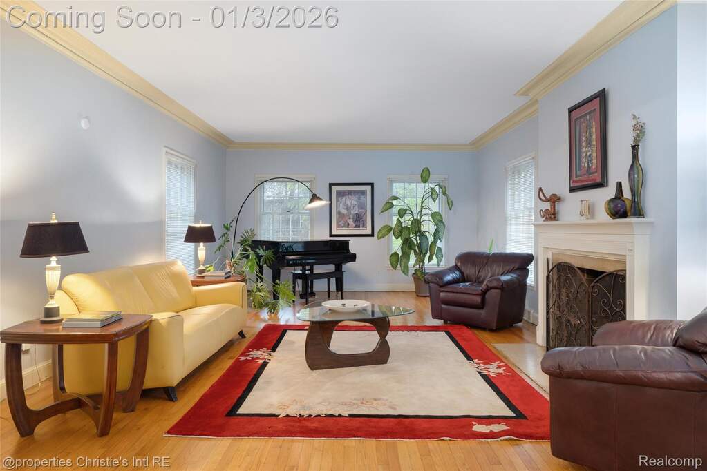 Living area with a fireplace with flush hearth, healthy amount of natural light, crown molding, and wood finished floors