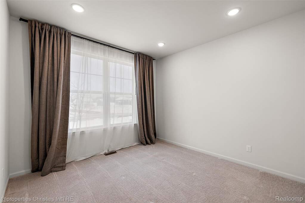 Empty room with light colored carpet and baseboards