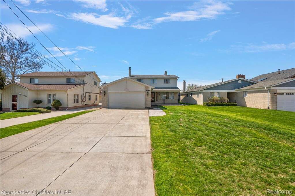 Traditional-style house featuring concrete driveway, a front lawn, a garage, and a residential view