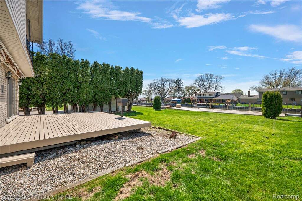 View of grassy yard featuring a deck and a residential view