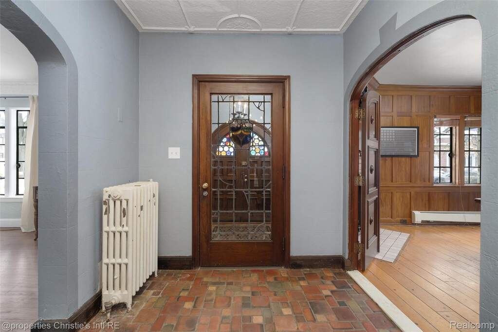 Entryway with arched walkways, radiator heating unit, a baseboard radiator, and crown molding