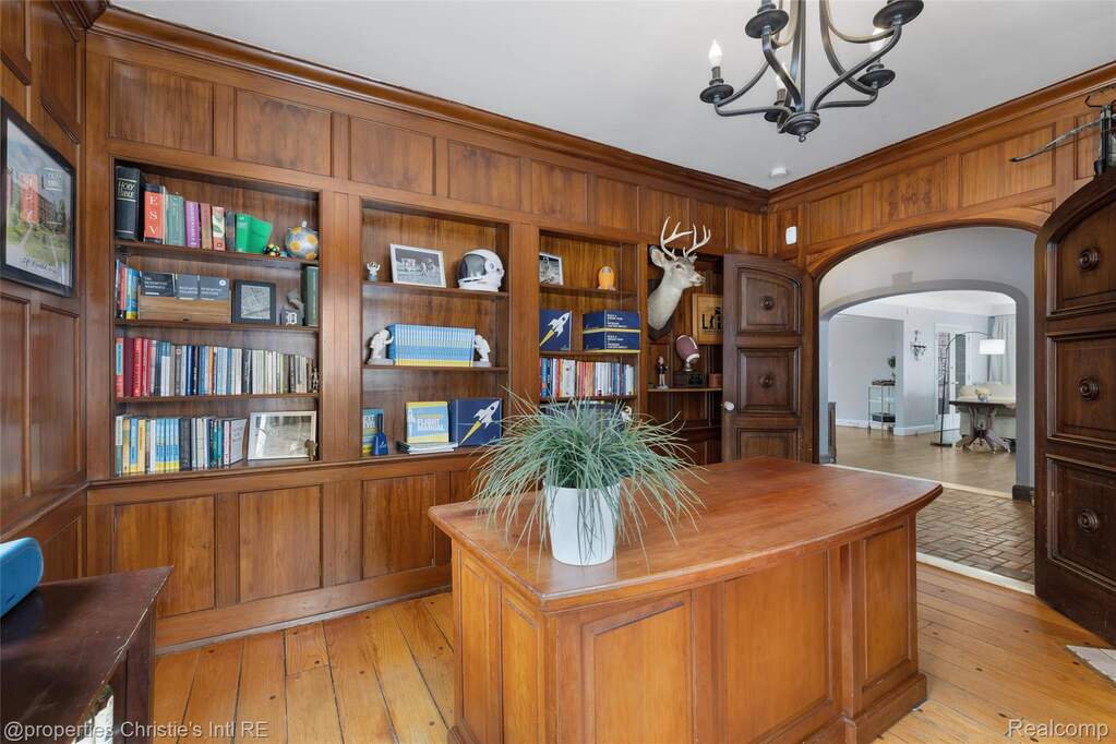 Office featuring arched walkways, light wood-style floors, ornamental molding, built in features, and a chandelier