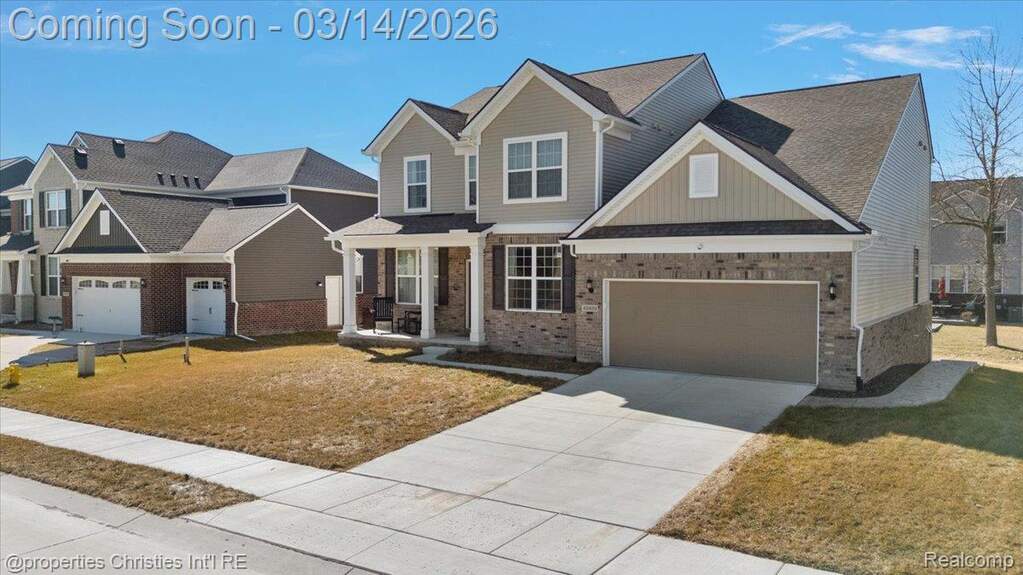 Craftsman house featuring a front yard, driveway, brick siding, a garage, and board and batten siding