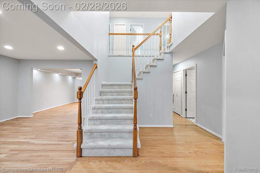 Stairway featuring wood finished floors, a high ceiling, and recessed lighting